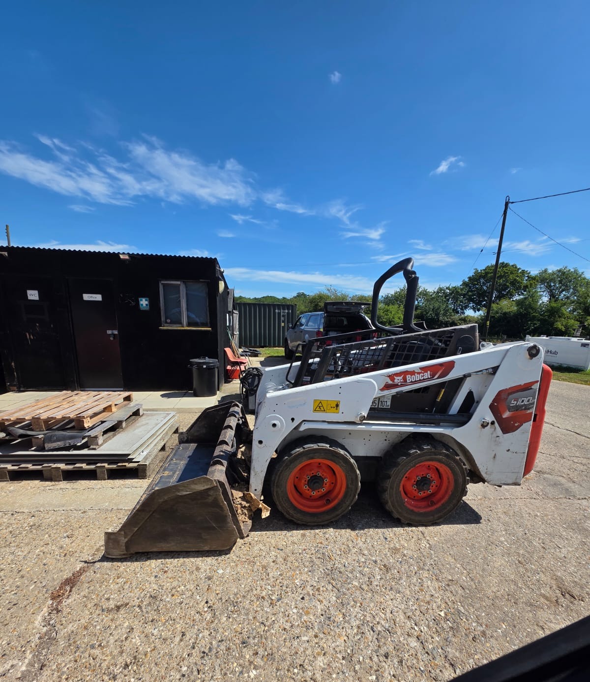 Bobcat S100 skid steer with bucket parked in the yard